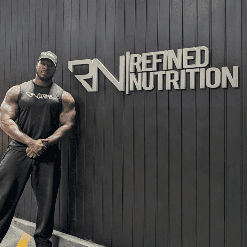 Syxx standing next to the Refined Nutrition logo at their head office